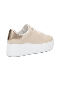 Sneaker in suede beige con una suola piatta bianca e un accentuazione del tallone dorato metallico. Presenta lacci bianchi e un design a punta arrotondata.