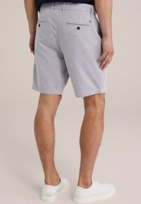 Gray woven shorts with two back pockets and black buttons, worn with white sneakers. The fabric has a subtle texture and casual fit.