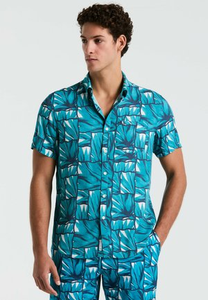 Chemise à manches courtes en tissu turquoise avec un motif géométrique de feuilles dans des teintes de bleu et de blanc, avec un devant boutonné et un col.