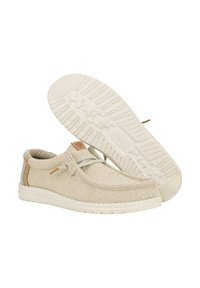 Scarpe in tela beige con una superficie testurizzata, caratterizzate da una punta rotonda, dettagli con lacci e una suola in gomma bianca con un motivo di battistrada.