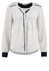 Blusa bianca con motivi geometrici neri, maniche lunghe, chiusura frontale con bottoni e dettagli neri a tinta unita su colletto e polsini. Tessuto testurizzato.