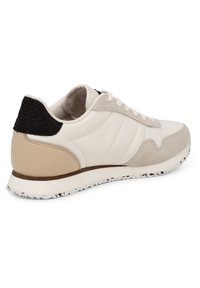 White leather sneaker with beige and black accents. Features a smooth finish, textured heel cap, and a rubber sole with a speckled design.