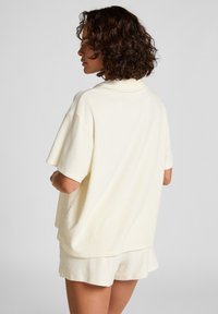 Korte mouw, crèmekleurig loungewear-set van zachte stof; heeft een ontspannen pasvorm met een polokraag en minimale stikdetails.