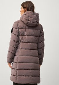 Abrigo acolchado marrón con capucha, que presenta secciones acolchadas, mangas largas y acentos de logo negro en el hombro y la espalda.