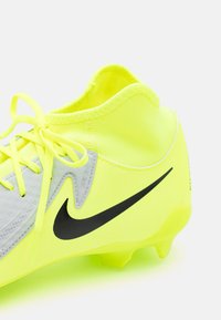 Nike futbola apavi spilgti dzeltenā krāsā ar pelēkiem akcentiem. Iezīmējas ar struktūru, melnu logotipu un izstrādātu potītes atbalsta dizainu.
