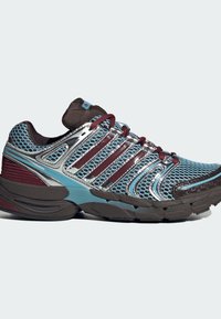 Hardloopschoen met een ademend mesh bovenwerk in blauw en zilver, bordeauxrode accentstrepen, een dempende zool en een getextureerde bruine buitenzool.