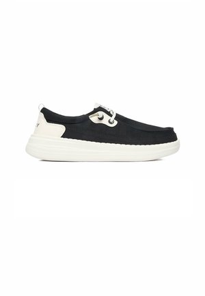 Chaussure slip-on décontractée noir et blanc avec lacets blancs et semelle blanche épaisse, vue de côté sur fond blanc.