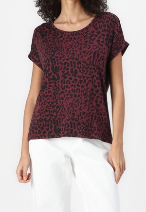 Czerwono-czarna koszulka z krótkim rękawem w cętki lamparta, z okrągłym dekoltem. Wykonana z miękkiego materiału, z luźnym krojem i podwiniętymi rękawami.