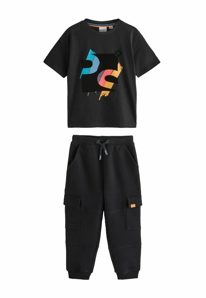 Musta T-paita, jossa on värikäs graafinen kuvitus, ja mustat collegehousut sivutaskuilla ja oranssilla tarralla. Puuvillakangasta, rentoa leikkausta.