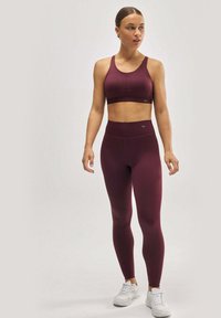 Conjunto de sujetador deportivo y leggings en color marrón, hecho de una tela suave y elástica; diseño ajustado con cintura alta; combinado con zapatillas blancas.