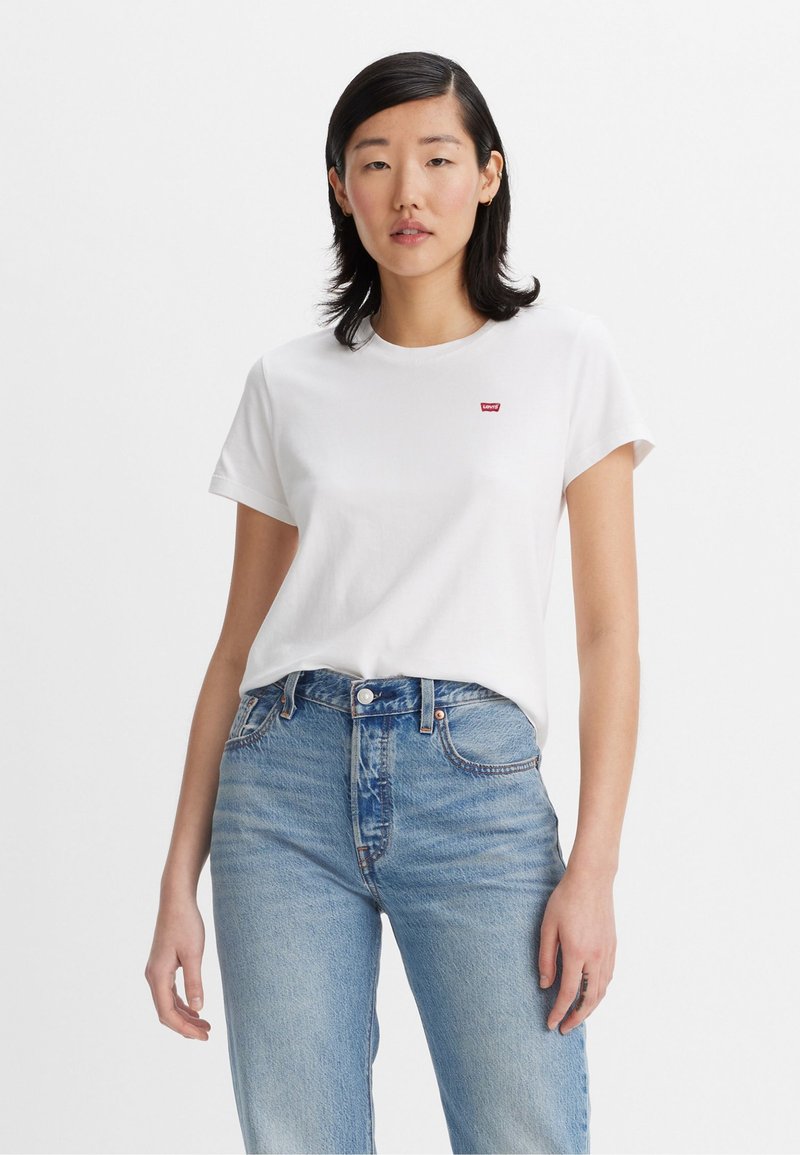 Weißes Baumwoll-T-Shirt mit kurzen Ärmeln, versehen mit einem kleinen roten Levi's-Logo auf der linken Brust, kombiniert mit hellblauen Denim-Jeans.
