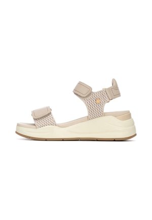 Sandalias beige con parte superior de malla y correas ajustables de velcro, con una suela acolchada blanca y beige con fondo texturizado para mayor agarre.