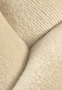 Textured beige fabric with soft and plush surfaces, featuring a blend of smooth and ribbed patterns.