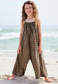 Sort blomsterprint jumpsuit med smocked halsudskæring, brede ben og et svævende design, der har små rose mønstre i livlige farver.