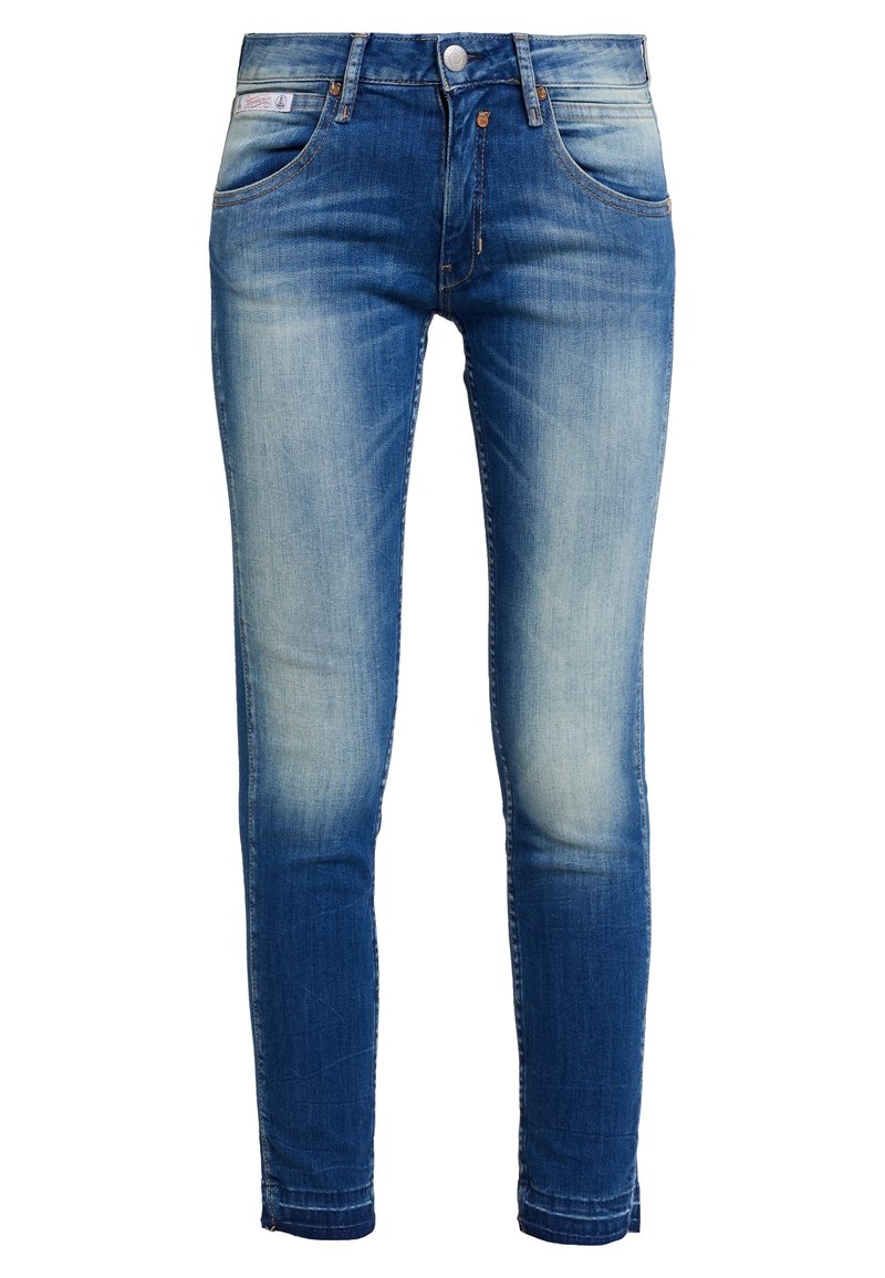 Jean skinny bleu délavé avec fermeture à bouton et zip devant, style cinq poches, avec légère usure aux cuisses et aux genoux.