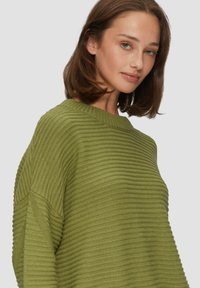 Olijfgroen trui met een gestructureerd ribgebreid ontwerp, brede halslijn en oversized pasvorm. Zachte gebreide stof met een drop shoulder-ontwerp en een ontspannen silhouet.