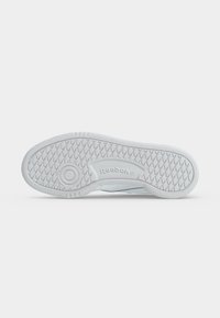Suela blanca de zapatilla Reebok con patrón de dibujo en forma de diamante, diseño de agarre circular y logo Reebok en relieve en el centro.