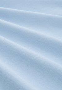 Ljusblått tyg med en jämn yta och lätt glans, som visar subtila vävda mönster och sviktande veck.