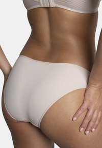 Sous-vêtements beiges sans coutures avec une texture lisse et une taille élastique, affichant un design à cuissardes hautes et des détails de couture minimaux.