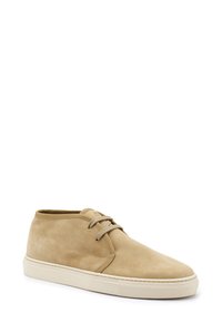 Stivali alla caviglia in suede beige con punta rotonda, suola in gomma piatta e design classico con lacci. Texture liscia, estetica minimalista.