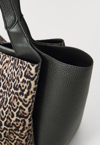 Fekete bőrtáska leopárdmintás textil panellel. Strukturált formájú, dupla fogantyúval és cipzáras nyitással rendelkezik.
