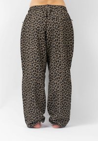 Leopardprintbroek in bruin en zwart stof. Heeft een losse pasvorm met een elastische tailleband en zijzakken. Zachte textuur, wijd been ontwerp.