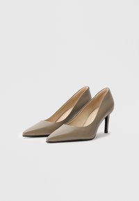 Μπεζ ψηλοτάκουνα παπούτσια με κοφτό μπροστινό μέρος και λείο συνθετικό φινίρισμα, λεπτό μαύρο στιλέτο τακούνι και μινιμαλιστικό σχέδιο. Μαλακό μπεζ εσωτερικό.