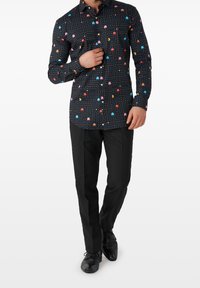 Zwarte lange mouwen shirt met een Pac-Man geïnspireerde print met kleurrijke stippen en personages; gedragen met zwarte broek en schoenen.