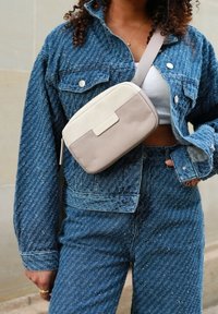 Giacca di jeans con un motivo testurizzato, abbinata a jeans a vita alta coordinati. Una borsa a tracolla beige con un'accento in pelle liscia.