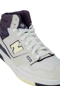 Witte en grijze sneaker met een hoge ontwerp, voorzien van mesh- en suede-texturen, een prominent logo en veters. Modelnummer: 650.