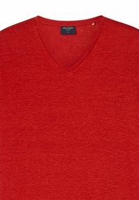 T-shirt rosso a scollo a V con un tessuto morbido e texture. L'etichetta riporta "OLYMP CASUAL," taglia M. Design semplice, senza motivi o accenti aggiuntivi.