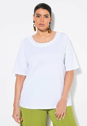 Hvid kortærmet t-shirt med bølget halsudskæring og plisseret detalje. Bæres med grønne teksturerede bukser med vidde.