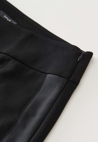 Jupe en tissu noir avec une texture lisse, un panneau latéral en satin contrastant et un zip discret à la taille.