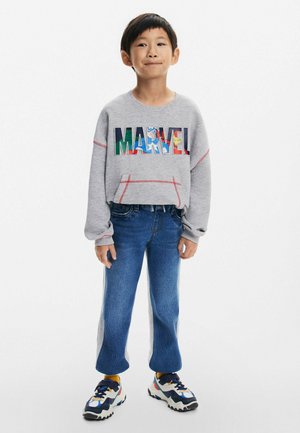 Gray sweatshirt with multicolor "MARVEL" graphic, light blue jeans with side stripe, and black and white sneakers with colorful accents.
