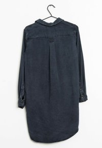 Mørkeblå denim skjortekjole med lange ærmer, knapmanchetter, krave og plissédetalje bagpå. Glat tekstur og buet talje.