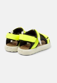 Lätta sandaler med en neongul textilöverdel, svarta detaljer, justerbara remmar, korkinsåle och en vit gummisula.