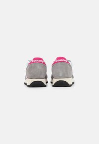 Grå ruskinds sneakers med en hvid mellemsål og sort ydersål. Hælen har et pink "Saucony" logo som accent.