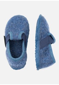 Blauwe fuzzy kinderslippers met elastische banden en getextureerde rubberen zolen, weergegeven vanuit boven- en zijkantzicht op een witte achtergrond.
