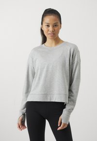 Grå kortermet genser laget av myk stoff, med rund hals, lange raglan-sarmer med tommelhull, og en subtil teksturfinish.