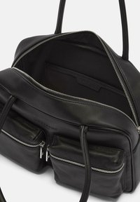 Sac à main en cuir noir avec fermeture éclair, deux poches avant et intérieur uni. Présente une texture lisse et des poignées doubles robustes.