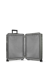 Valise rigide en vert muted avec une finition texturée. L'intérieur présente des poches en maille grise et deux compartiments avec un séparateur central.