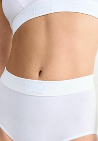 Weiße Baumwoll-Hüfthose mit hohem Bund und weich elastischem Bund. Verfügt über ein dezentes Logo-Tag, eine glatte Textur und zarte Spitzenbesätze an den Beinöffnungen.
