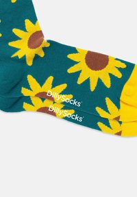 Farverige sokker med en teal baggrund prydet med gule solsikker og brune midterpunkter. "DillySocks" branding trykt i hvidt.