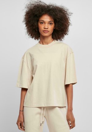 Lys beige oversized t-skjorte med rund hals og korte ermer, laget av myk bomullsstoff, med minimale sømdetaljer.