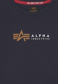 Felpa blu navy con un logo marrone prominente che mostra una 'A' e tre strisce orizzontali. Girocollo e tessuto morbido.