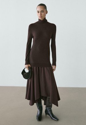 Brown turtleneck sweater dress with long sleeves, a flared skirt, paired with black pointed-toe boots and a small black handbag.