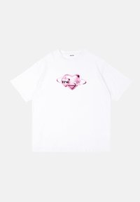 Hvid kortærmet t-shirt med et pink hjertegrafik og et omkransende design samt teksten "trust" i sort. Fremstillet af bomuld.