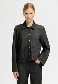 Black denim jacket featuring a collared neckline, front button closure, two large pockets, and long sleeves. Textured fabric with a cropped fit.