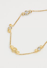 Goldene Halskette mit glatten, runden Gliedern und Akzentsteinen, darunter klare und hellblaue Elemente, an einer zarten Kette.