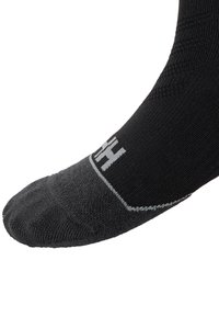 Calcetín negro hasta el tobillo con un cuerpo texturizado, punta gris y logo blanco. Presenta costuras reforzadas y un ajuste ceñido.